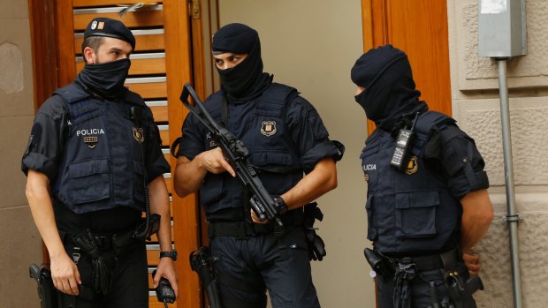 Police officers stand outside a building during a search in Ripoll, north of Barcelona.