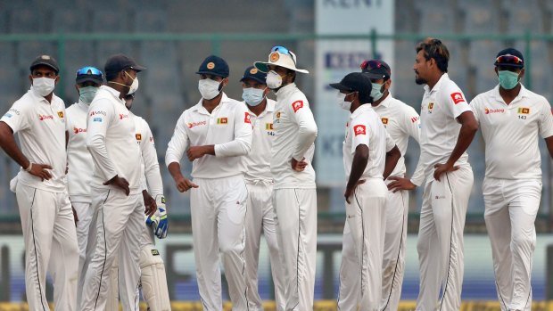Sri Lankan players, wearing anti-pollution masks, during the fourth day of their third test cricket match in Delhi, India.