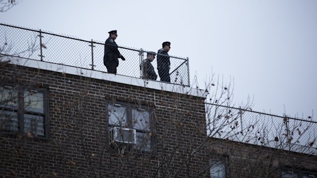 Keeping watch: Police view the scene from the rooftop of a building.