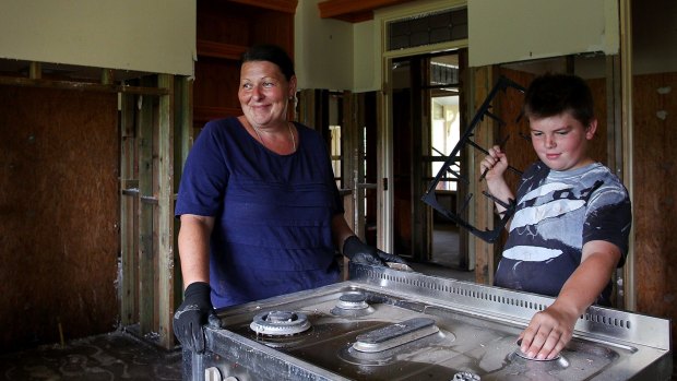 Ms Gallo and son Zander Gallo in their flood damaged kitchen where 1.5 metres of water washed through.