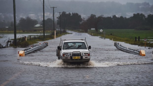 Local farmer crosses the flooded Illawarra Highway at Albion Park after heavy falls across the region.