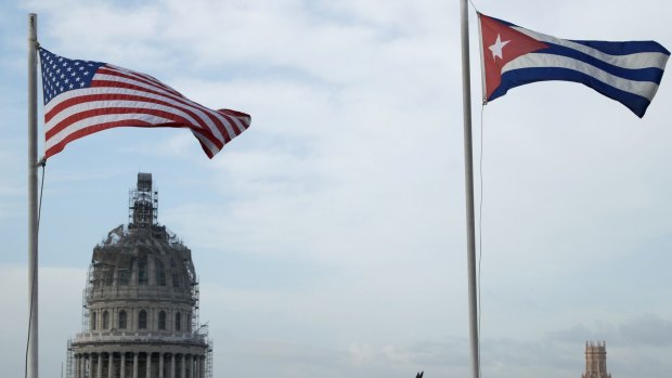 United States and Cuban flags fly side-by-side on the roof of a hotel in the historic Old Havana.