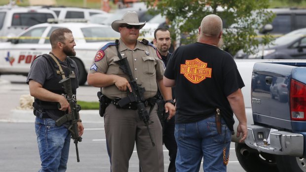 Law enforcement officers talk to a man near the parking lot of the Waco restaurant. 