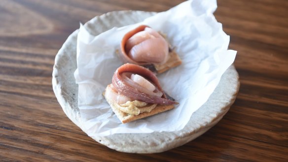 Anchovy and shallot on brown butter cracker.