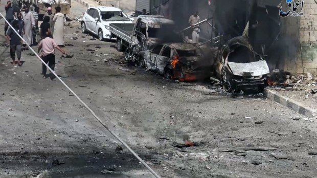 Syrian citizens gathered near burned cars after airstrikes hit Manbij, in Aleppo province, Syria.