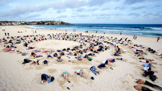 Protesters bury their heads in the sand at Bondi Beach to send a climate change message to Tony Abbott during the G20 Summit in Brisbane.