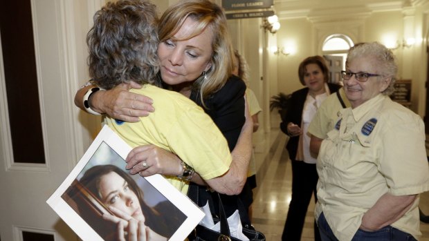 Debbie Ziegler holds a photo of her late daughter, Brittany Maynard, as she receives congratulations from Ellen Pontac, left, after the right-to die bill was approved by the state Assembly in Sacramento, California.