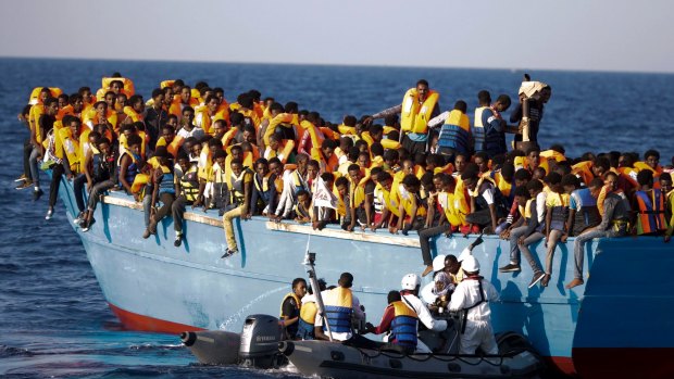 Italian officers rescue a woman from a crowded wooden boat carrying more than seven hundred migrants, during a rescue operation in the Mediterranean, off Libya last month. 