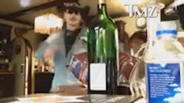 Johnny Depp reaches for a bottle of wine in the video.