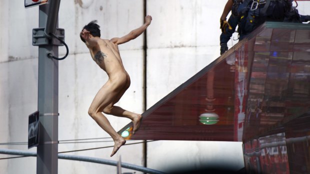A naked man jumps off the rear staircase ledge above the TKTS Broadway ticket booth in New York's Times Square.