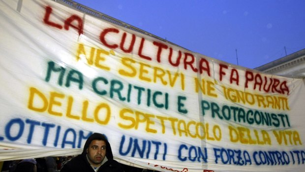 A man stands under a banner protesting cuts to Italy's national budget for culture outside Milan's La Scala opera house in 2010. 
