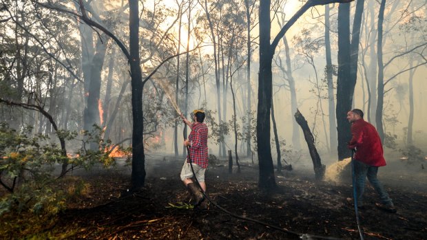 Adam Watkins and partner Prue Mathiesen fight the fire to save their rented home in Lancefield.