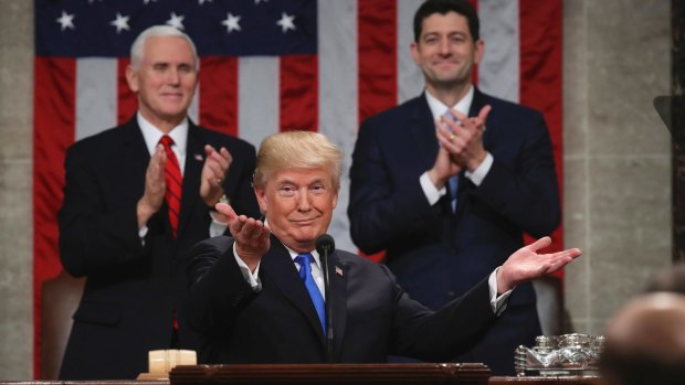 President Donald Trump gestures as Vice President Mike Pence and House Speaker Paul Ryan applaud.