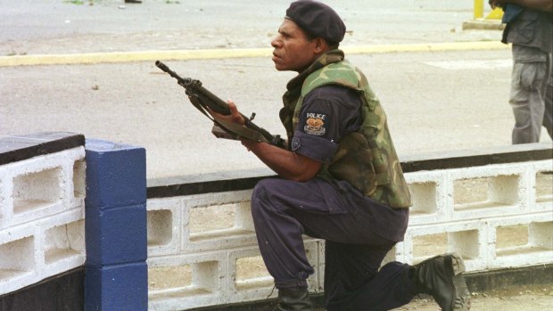 A riot policeman takes cover outside Murray Army Barracks in Port Moresby.