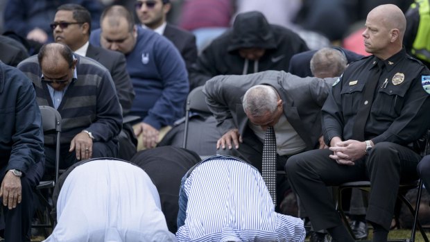 Chapel Hill police chief Chris Blue (right) listens as people pray during a service in a soccer field near the Islamic Association of Raleigh in Raleigh, North Carolina. 