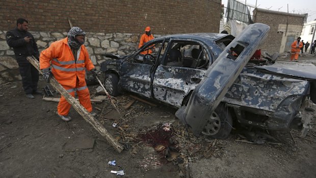 Afghanistan's municipality employees, in orange, clean up the site of a suicide attack claimed by the Taliban at Le Jardin, a French restaurant, in Kabul, earlier this month.