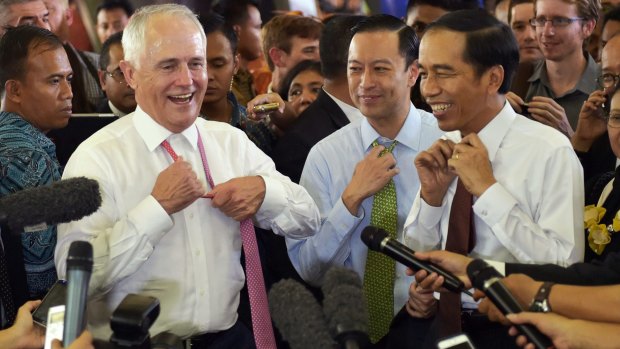 Australian Prime Minister Malcolm Turnbull and Indonesian President Joko Widodo move to take off their ties during a visit to a Jakarta market. Standing between them in the blue shirt is Thomas Lembong.