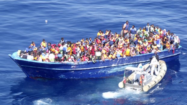 In this photo provided by the Italian Navy, migrants are approached by an Italian Navy dinghy in the Mediterranean sea on Saturday.