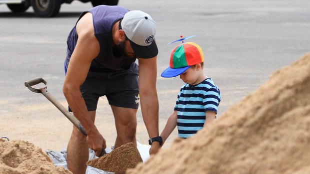 Orlando Bryson helps his dad, Dylan, with the sandbagging.
