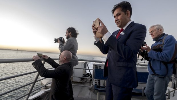 Passengers record the ferry's first regular trip. 