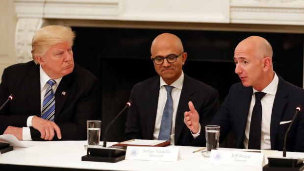 Not much love lost: Donald Trump (with Microsoft CEO Satya Nadella in the centre) listens to Amazon boss Jeff Bezos during an American Technology Council roundtable at the White House in June.