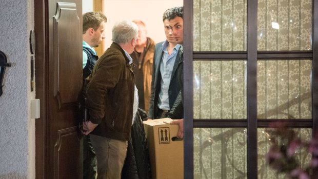 Police carry computer, a box and bags out of the home of the parents of Andreas Lubitz.