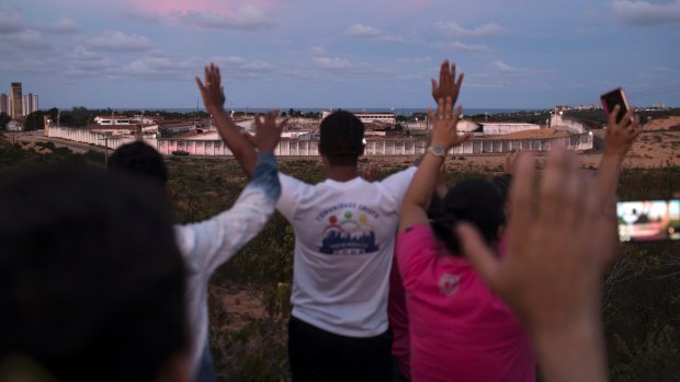 People pray for peace toward the Alcacuz prison in Nisia Floresta, near Natal, Brazil. 