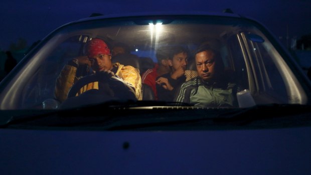 People sit inside their car on open ground to keep safe after an earthquake in Kathmandu.