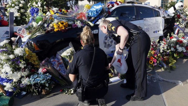 Dallas police Sergeants Amanda Renteria, left, and Laura Browning lay flowers and candles outside a Dallas Police Department.