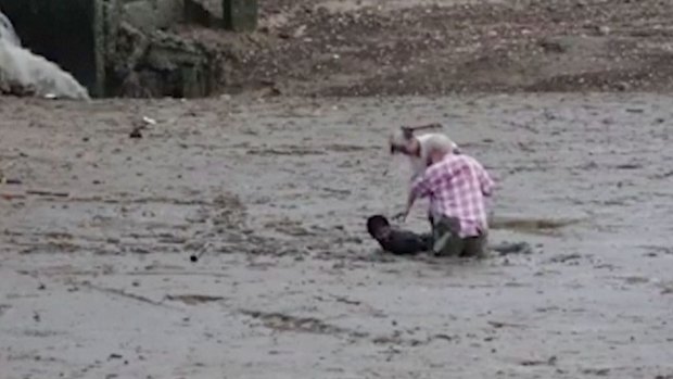 Thai construction worker Chat Ubonchinda lies in the mud as he helps two unidentified Norwegian bird watchers who were sinking into a mudflat in Krabi.