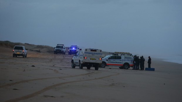 Police at the scene where two bodies washed up on Stockton Bight, believed to be those of two sailors missing since Thursday.