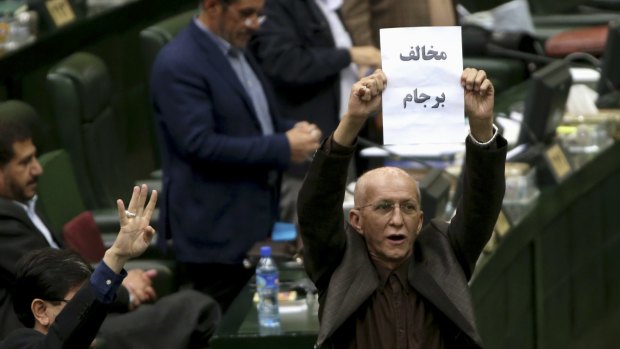 Iranian conservative lawmaker Bijan Nobaveh Vatan holds up a paper with writing in Persian reading, "Opponent of the JCPOA", an abbreviation of the Joint Comprehensive Plan of Action, referring to a nuclear deal of Iran and world powers.