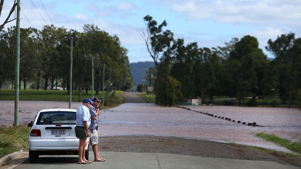 Men stand at the edge of floodwaters in Beaudesert.