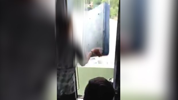 A still from the video showing teens throwing a seat from a moving train.