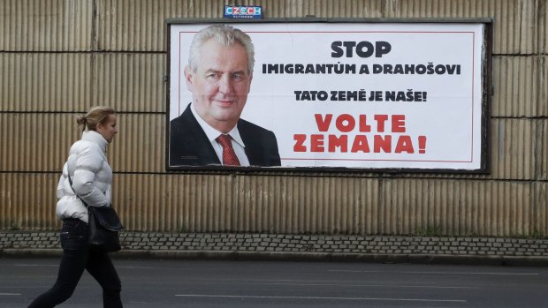 A woman walks past an anti-immigration poster for Czech President Milos Zeman.