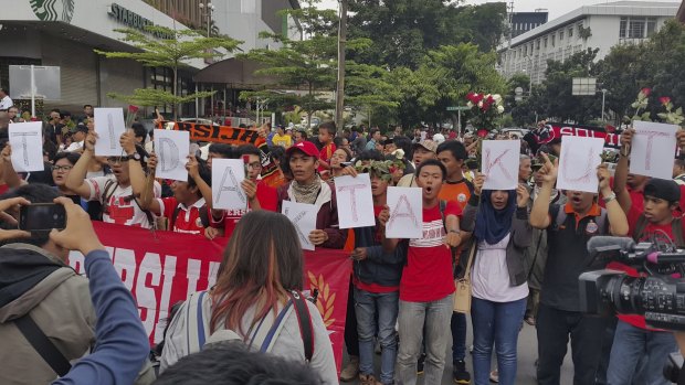 Jakarta Football Club supporters sing while holding letters saying "kami tidak takut" (We are not afraid) at a vigil at the site of the Jakarta terror attack.