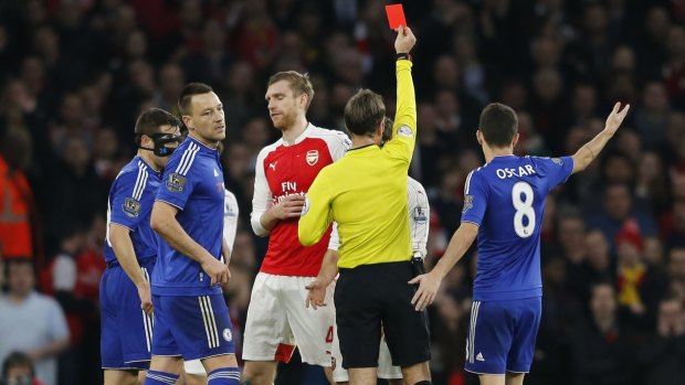 Arsenal's Per Mertesacker, centre, is shown a red card  and sent off by referee Mark Clattenburg for a foul on Chelsea's Diego Costa.
