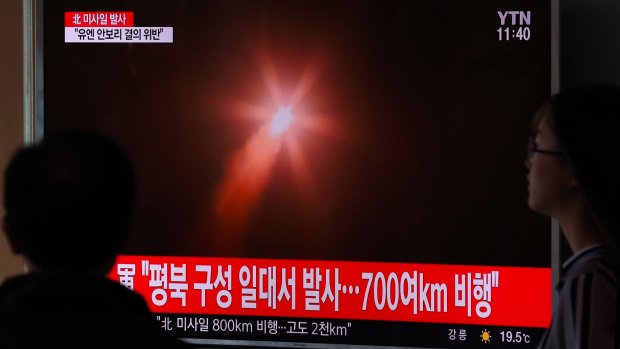 People watch a television screen showing a news broadcast on North Korea's ballistic missile launch  on May 14.