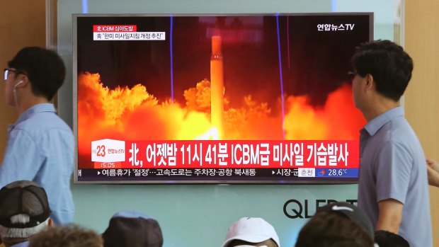 People watch a TV news program showing an image of North Korea's latest test launch of an intercontinental ballistic missile (ICBM), at the Seoul Railway Station.