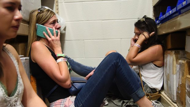 Women make phone calls while taking shelter inside the Sands Corporation plane hangar after the mass shooting in Las Vegas.