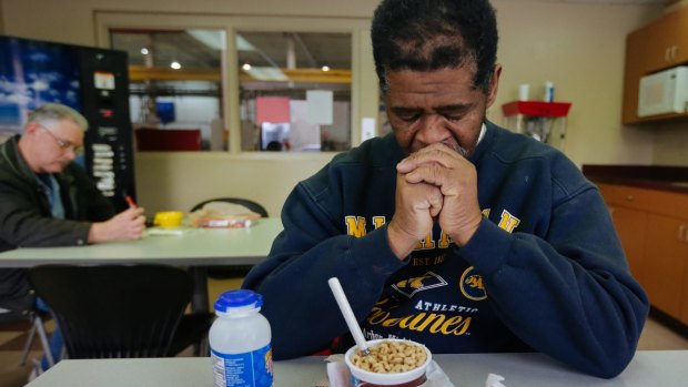 James Robertson prays before eating in the break room before his shift at Schain Mold & Engineering in Rochester Hills, Michigan.