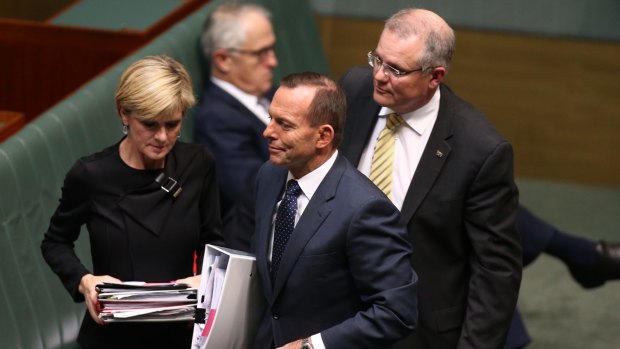 Prime Minister Tony Abbott departs question time with Julie Bishop and Scott Morrison while Malcolm Turnbull remains on the frontbench.