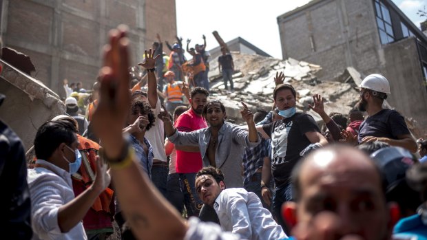 People react in front of a collapsed building following the earthquake in Mexico City.