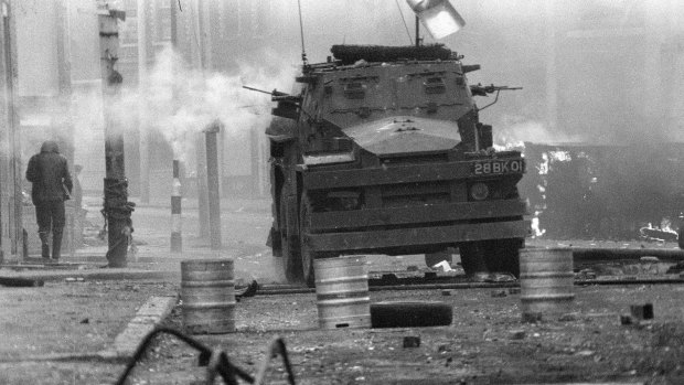 A British Army armoured vehicle makes its way along a barricade while on patrol in the Lower Falls area of west Belfast. Trouble in the area erupted after the shooting of Joe McCann the previous day. 