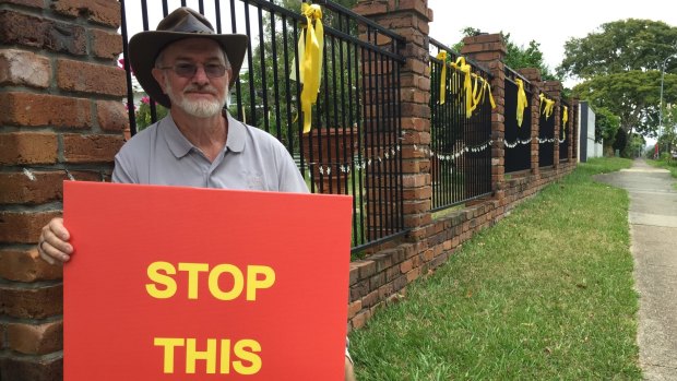 Carseldine resident Barry Gilmore with his campaign sign and bright yellow ribbons, which decorate the outside of his property.