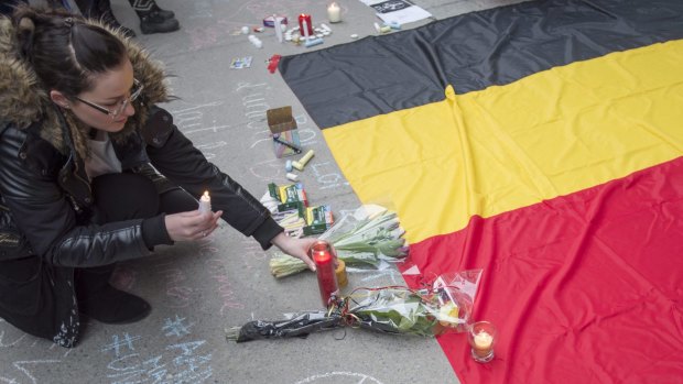 A woman places a candle next to a Belgian national flag during a vigil in Montreal on Wednesday.