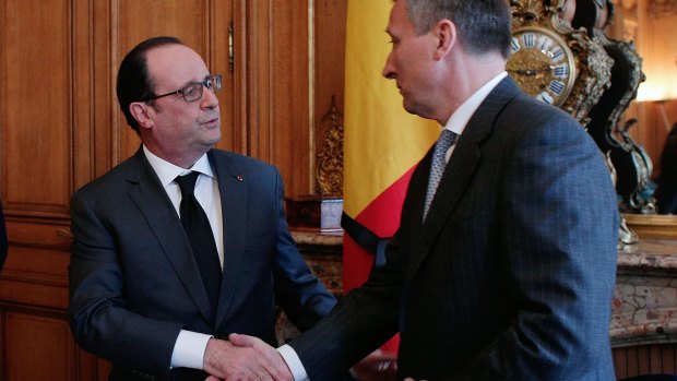 French President Francois Hollande shakes hands with Belgium Ambassador to France Vincent Mertens.