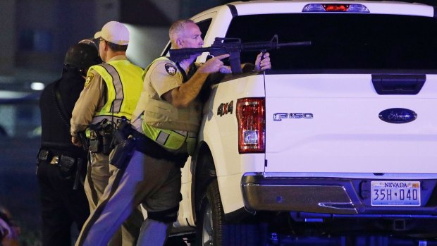 A police officer takes cover behind a truck at the scene of a shooting  on the Las Vegas Strip. 