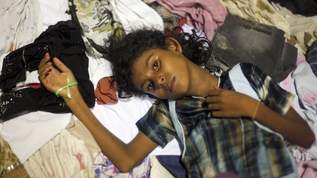 An ethnic Rohingya girl lies down on used clothing donated by local residents at a sports stadium turned into temporary shelter for migrants whose boats washed ashore on Sumatra island in Aceh province, Indonesia.