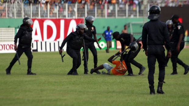 Police detain an Ivory Coast fan.